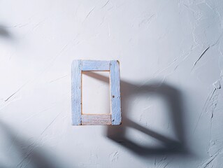 Empty light-blue and beige wooden picture frame on textured white background, casting shadows