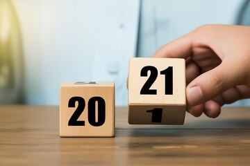 Naklejka premium Hand turning wooden blocks; transitioning from 20 to 21; new year, new beginnings; optimistic, hopeful mood; business concept.