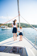 Mother and daughter spending time together on the bow of a sailing yacht. Family bonding, sea...