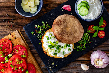 Cottage cheese roll with fresh herbs on stone board on wooden table