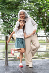 Obraz premium Old woman grandmother holding hand standing with kid girl granddaughter at railing around the lake.