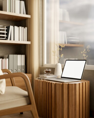 Blank screen laptop and coffee on tree stump table with armchair and bookshelf in sunlit living room