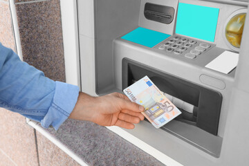 Male hand withdrawing euro banknotes from ATM outdoors, closeup