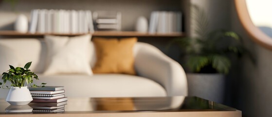Plant in pot and notebook on glass top wooden table and sofa aside bookshelf in a sunlit living room © bongkarn