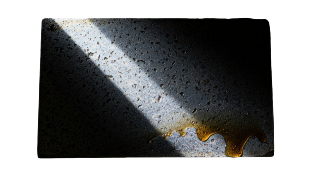 Rough, pitted dark grey industrial steel sheet with oily residue pooling, intensely lit by a piercing diagonal fluorescent light, on white background with copy space, concept of urban decay