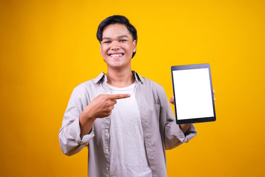 Attractive Young Asian Male Pointing And Showing Digital Tablet With Blank White Screen