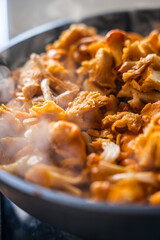 Close-up of chanterelle mushrooms cooking in a pan with visible steam rising