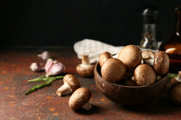Wooden bowl with fresh raw mushrooms and rosemary on grunge table