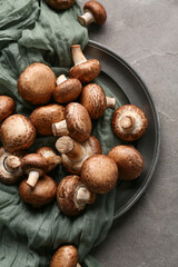 Plate with fresh raw mushrooms on grey background