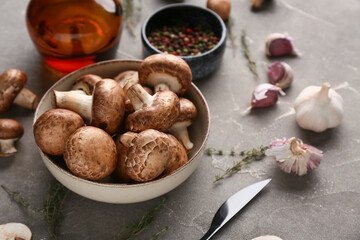 Bowl with fresh raw mushrooms, peppercorns and thyme on grey background, closeup