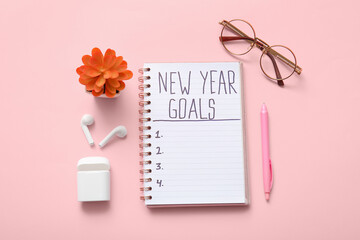 Notebook with text NEW YEAR GOALS and eyeglasses on pink background