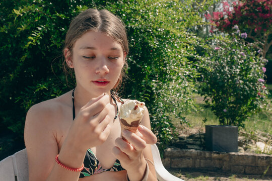 Beautiful young girl enjoying an ice cream cone in a tropical setting
