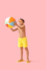 Cute little boy playing with beach ball on pink background