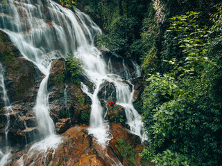 Fototapeta premium Aerial view of a beautiful waterfall in the middle of a forest in the pristine nature of the forest.