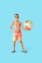 Adorable little boy with beach ball on blue background