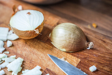 Chopped onion and knife on wooden cutting board in kitchen setting