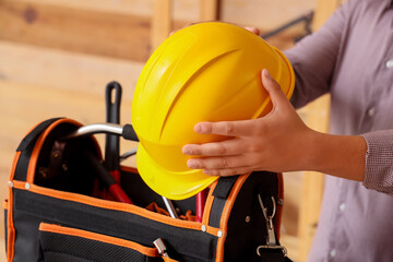 Man with hardhat and tool bag in workshop