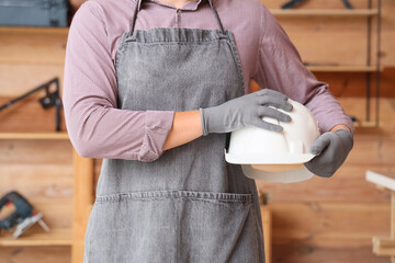 Man holding hardhat in workshop