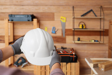 Male hands holding hardhat in workshop