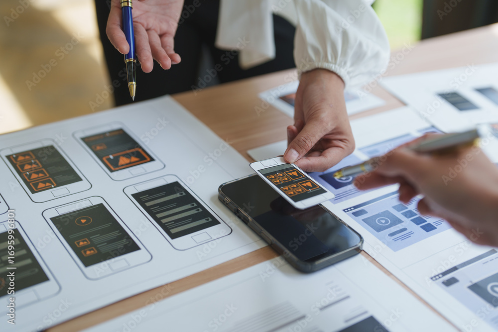 Poster web designers comparing mobile app prototype with sketch on paper