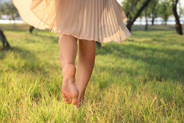Barefoot young woman walking on grass in park