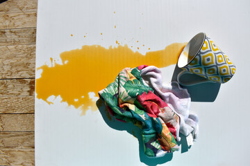 Overturned cup with spilled tea on a white surface and a cloth for wiping, top view