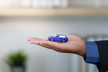 Car Dealership. A miniature car held in hand representing a vehicle purchase.