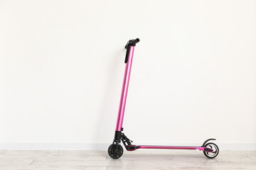 Modern electric scooter near white wall