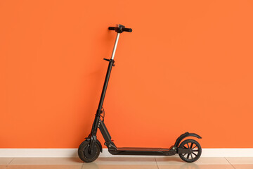 Modern electric scooter near orange wall