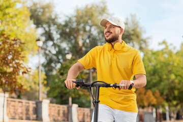 Handsome young man riding electric scooter at city street