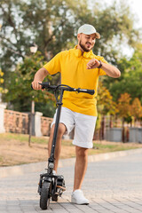 Handsome young man riding electric scooter at city street
