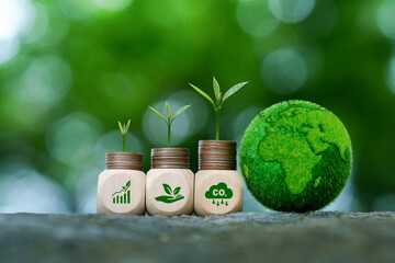 Plants growing on coin stacks next to a green Earth globe. Wooden blocks show ESG icons for CO2...