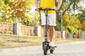 Young man riding electric scooter at city street