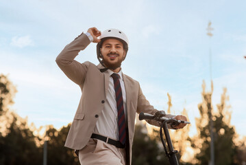 Handsome young businessman on electric scooter at city street