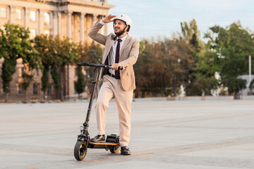Handsome young businessman on electric scooter at city street