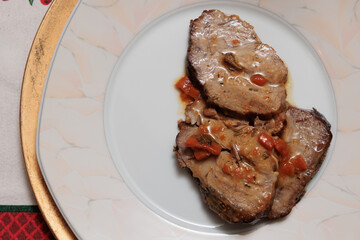 fette di arrosto di maiale con sugo e pezzi di carote, ricetta tradizionale natalizia italiana fatta in casa