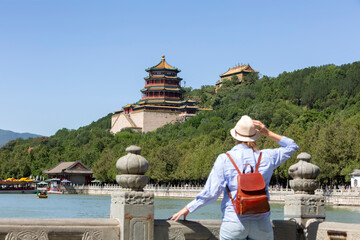 China Travel. A female traveler relaxing and enjoying the view of nature from an ancient Chinese temple, a tourist attraction in Beijing, China. Summer Palace tourism destination, travel to Asia.
