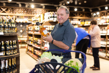 Elderly man choose bottle of alcohol