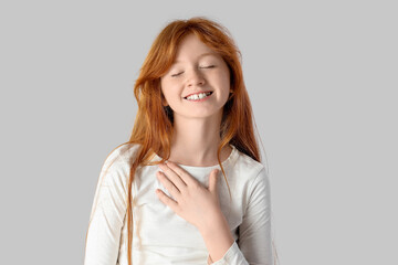 Portrait of cute teenage redhead girl on grey background