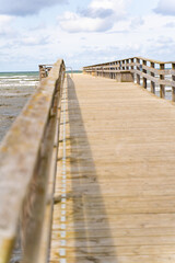 A picturesque wooden pier gracefully extending into the vast ocean beneath a vibrant sky and gentle waves, Bastad, Sweden