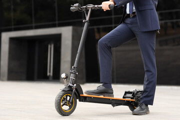 Young businessman on electric scooter near office building