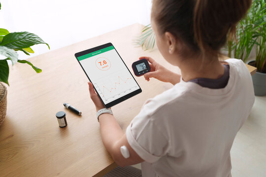 Woman with diabetes synchronizing tablet computer and glucometer at home