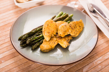 fried chicken breast pieces with asparagus on plate