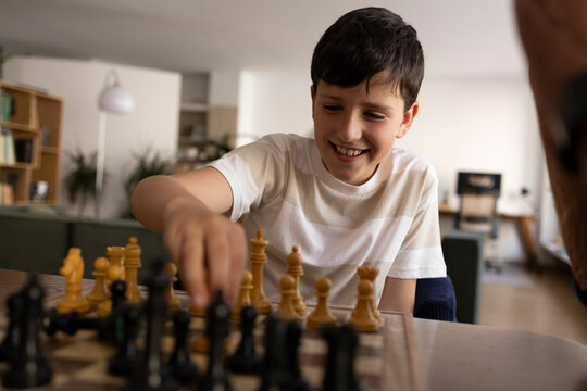 Grandfather and grandson playing chess together at home