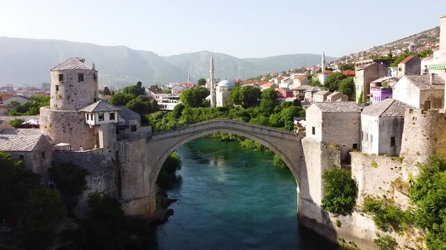 Aerial drone footage of the famous Mostar Bridge in Bosnia and Herzegovina, , the Neretva River below, and the historic town in summer