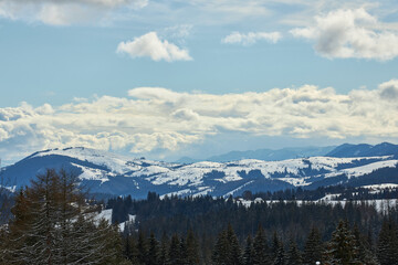 Majestic winter mountain range under a cloudy sky.