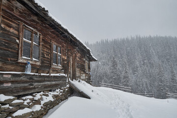 Rustic wooden cabin during a heavy winter snowstorm.