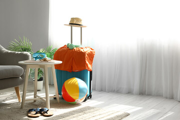 Suitcase with hat, headphones and men's swimwear in living room