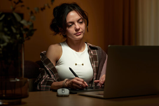 beautiful professional female retoucher woman working at home workspace using digital graphic tablet and laptop, post production software on graphic tablet.