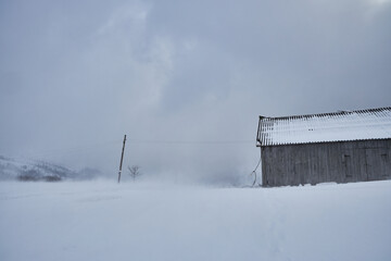 Rustic wooden cabin during a heavy winter snowstorm.